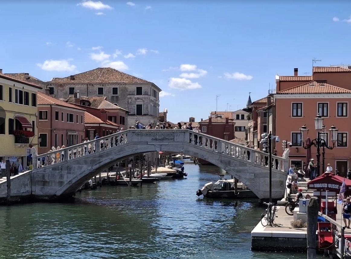 Stone bridge over a canal lined with colorful historic buildings in Chioggia